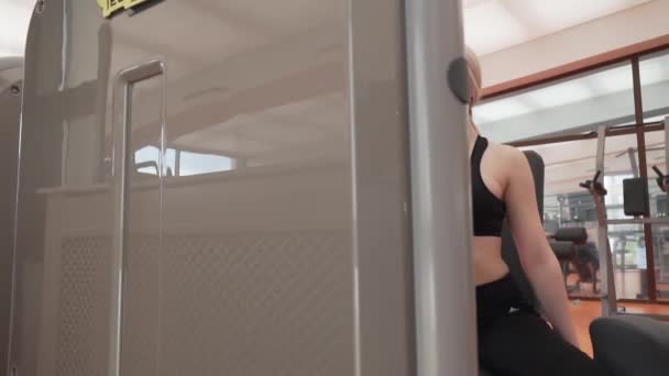 젊은 여자 코치 체육관 증권 영상 비디오에서 시뮬레이터에 다리의 근육 — 비디오