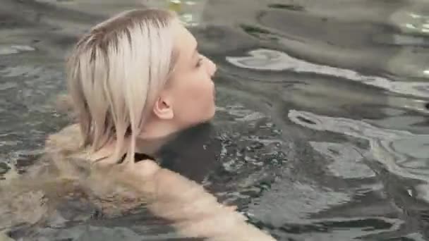 Hermosa chica joven nadando en la piscina material de archivo de vídeo — Vídeo de stock