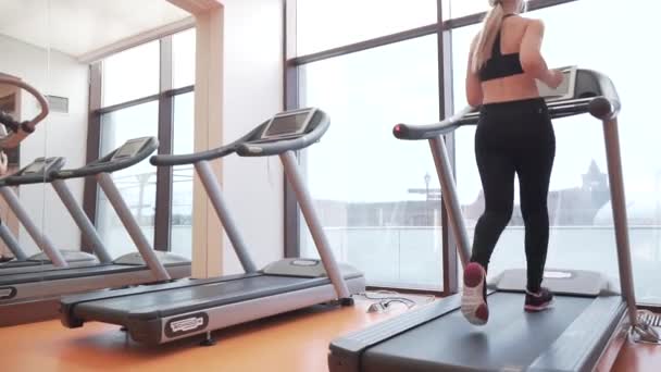 Молода дівчина тренується на біговій доріжці в спортзалі відеозапис — стокове відео