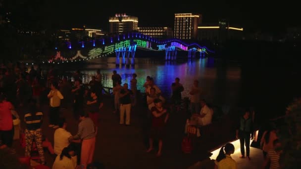 Kvällen danser av kinesiska och turister på banvallen av den Sanya floden arkivfilmer video — Stockvideo