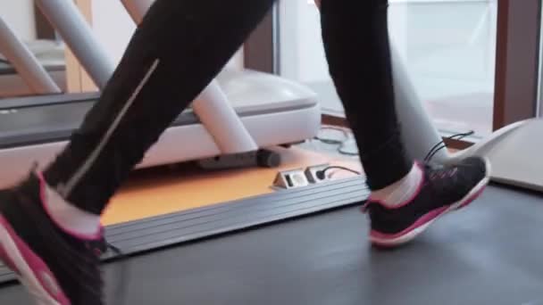 Chica joven entrena en una cinta de correr en el gimnasio material de archivo de vídeo — Vídeos de Stock