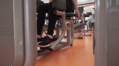 Genç kız spor salonu stok görüntüleri video simülatörde bacaklarına kaslarının Koçlar