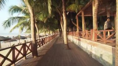 Şafak zaman atlamalı stok görüntüleri video, Dadonghai plajda palmiye ağaçları ile turistik sahil boyunca yürüyüş