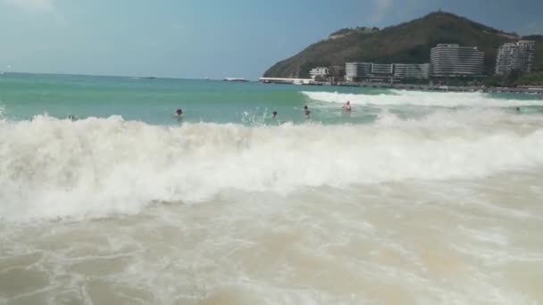Turisterna simma i starka vågor i Sydkinesiska havet på den Dadonghai Beach arkivfilmer video — Stockvideo