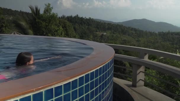 Jovem está nadando na piscina no topo de uma montanha imagens de vídeo — Vídeo de Stock