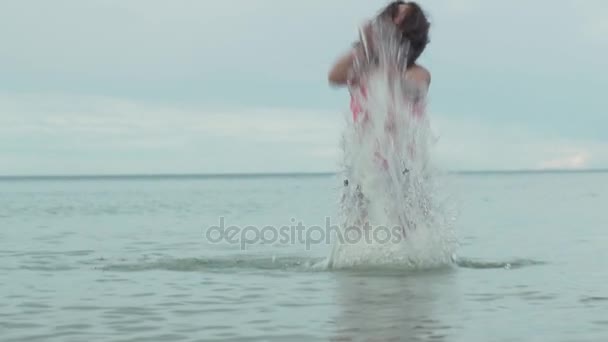 Vrolijke happy jong meisje spelen met opspattend water in zee slowmotion stock footage video — Stockvideo