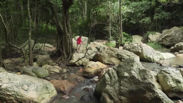 Young girl walks the rocks at Na Muang Waterfall on Koh Samui in Thailand stock footage video — Stock Video