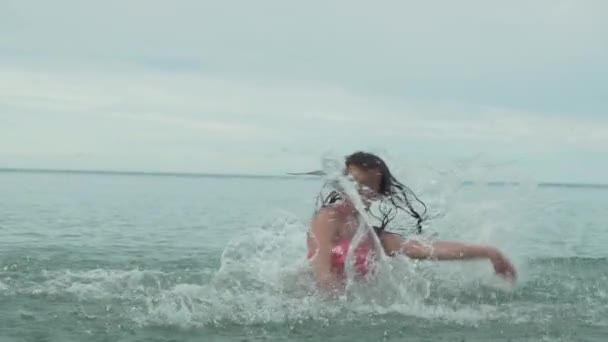 Neşeli mutlu genç kız deniz yavaş hareket hisse senedi görüntüleri video su sıçramasına ile oynamak — Stok video