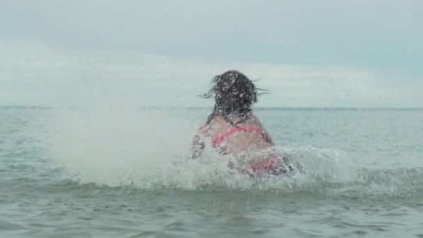 Alegre feliz joven jugando con salpicaduras de agua en el mar cámara lenta material de archivo de vídeo — Vídeos de Stock