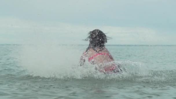 Alegre feliz joven jugando con salpicaduras de agua en el mar cámara lenta material de archivo de vídeo — Vídeo de stock