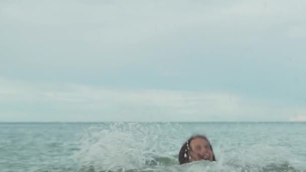 Χαρούμενη happy νεαρό κορίτσι παίζει με εκτοξευμένο νερό στη θάλασσα πλάνα Χρηματιστήριο αργή κίνηση βίντεο — Αρχείο Βίντεο