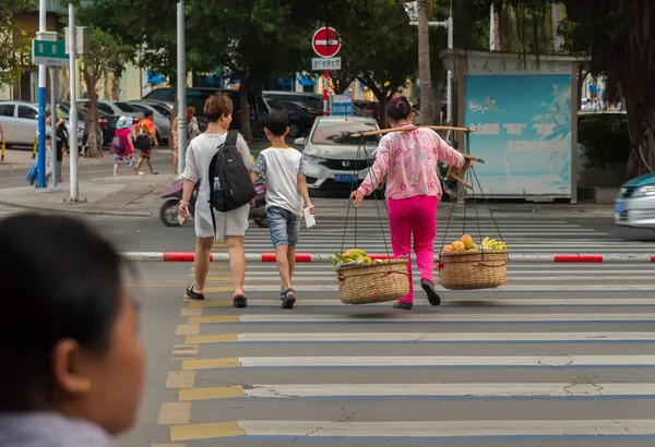 Kadın Sanya turistik şehir sokakta bir meyve sepeti taşır