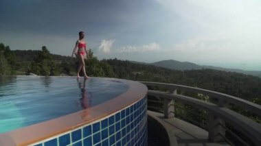 Bir dağ stok görüntüleri video üstüne havuz kenarı boyunca genç kız yürüyor