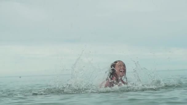 Vrolijke happy jong meisje spelen met opspattend water in zee slowmotion stock footage video — Stockvideo