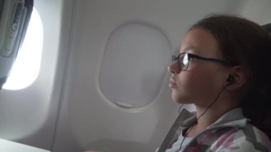 Video uçak stok görüntüleri video kabinde koltuk yerleşik monitör genç kız gözlük ve kulaklıklar ile izliyor