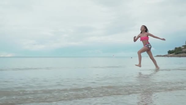 Radostné šťastná mladá dívka běží na vodě moře sprej zpomalené stopáže videa — Stock video