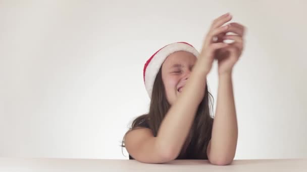 Caprichosa chica histérica adolescente en un sombrero de Santa Claus está llorando y exige el deseado en el fondo blanco archivo de vídeo — Vídeo de stock