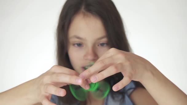 Hermosa alegre adolescente chica jugando con verde fidget spinner en blanco fondo material material material vídeo — Vídeos de Stock