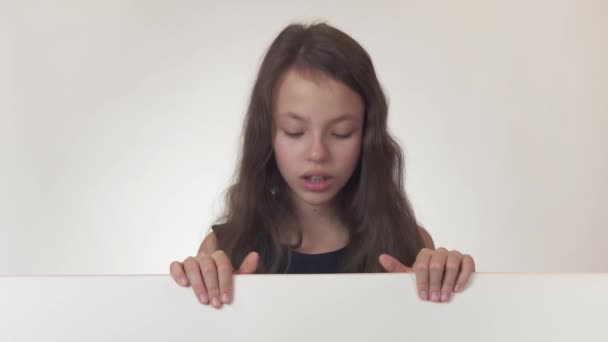 Schöne Mädchen Teenager sieht sich ein Plakat mit Informationen und drückt Unzufriedenheit und Wut auf weißem Hintergrund Stock Footage Video. — Stockvideo