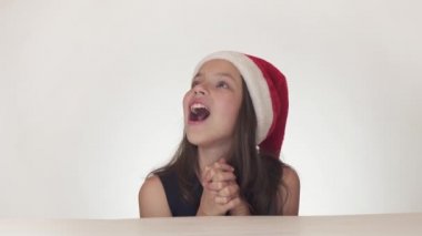 Güzel mutlu kız genç bir Noel Baba şapkalı duygusal neşeli sürpriz üzerinde beyaz arka plan stok görüntüleri video ifade..