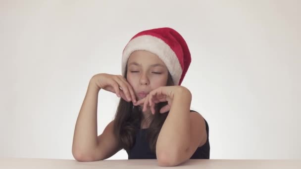 Mooie tiener meisje in Kerstman hoed verslikte op New Years sneeuwvlok op witte achtergrond stock footage video — Stockvideo