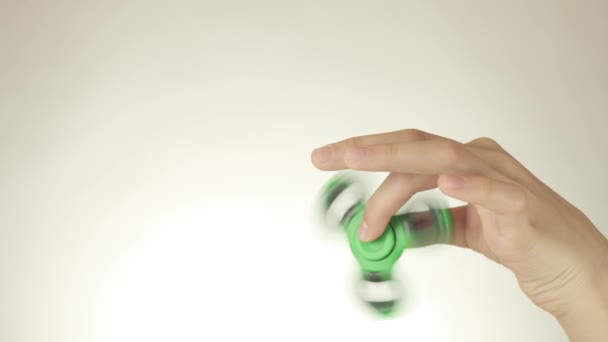 Hands of a teenage girl spin a green fidget spinner on white background stock footage video — Stock Video