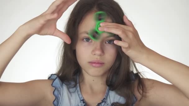 Vackra glada teen flicka spinning en grön rastlösa spinner på pannan på vit bakgrund arkivfilmer video — Stockvideo