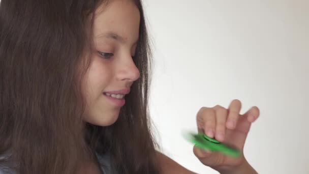 Bella ragazza adolescente allegra che gioca con filatore di fidget verde su sfondo bianco stock filmato video — Video Stock