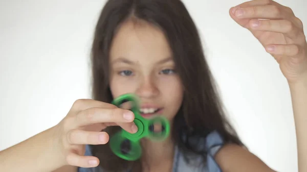 Schöne fröhliche Teenager-Mädchen spielen mit grünen Fidget Spinner auf weißem Hintergrund — Stockfoto