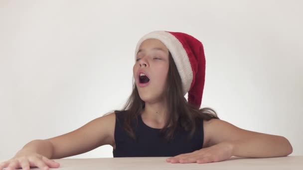 Güzel mutlu kız genç bir Noel Baba şapkalı duygusal bir sürpriz üzerinde beyaz arka plan stok görüntüleri video ifade.. — Stok video