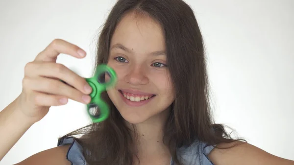 Bela menina adolescente alegre jogando com fidget spinner verde no fundo branco — Fotografia de Stock