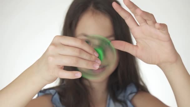 Hermosa alegre adolescente chica jugando con verde fidget spinner en blanco fondo material material material vídeo — Vídeos de Stock