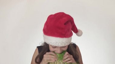 Güzel yaramaz kız genç bir iştahla Noel Baba şapkalı bir filiz yulaf üzerinde beyaz arka plan stok görüntüleri video yiyor..