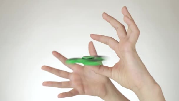 Händerna på en tonårig flicka snurra en grön fidget spinner på vit bakgrund arkivfilmer video — Stockvideo