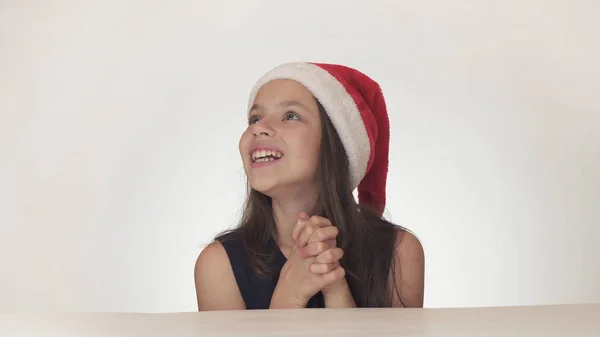 Bella ragazza felice adolescente in un look cappello di Babbo Natale ed esprime emotivamente una sorpresa su sfondo bianco — Foto Stock