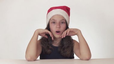 Güzel mutlu kız genç bir Noel Baba şapkalı duygusal neşeli sürpriz üzerinde beyaz arka plan stok görüntüleri video ifade..