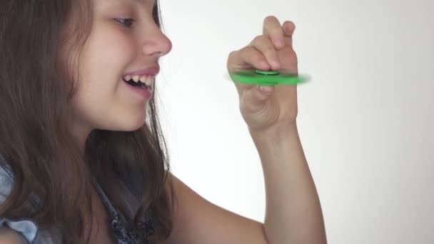 Beautiful cheerful teen girl playing with green fidget spinner on white background stock footage video — Stock Video