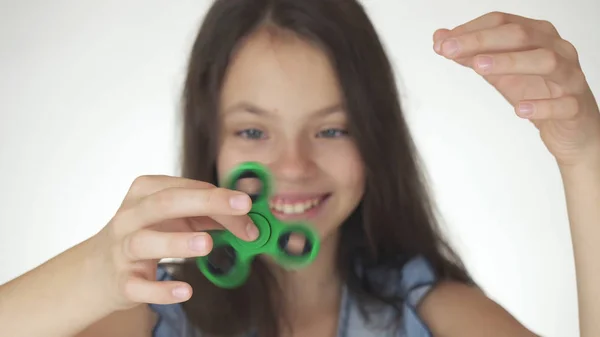 Bela menina adolescente alegre jogando com fidget spinner verde no fundo branco — Fotografia de Stock