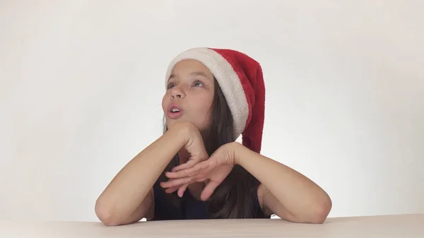 Nastolatek piękny szczęśliwy dziewczyna w kapeluszu Mikołaj wyglądać i emocjonalnie wyraża zdziwienie na białym tle — Zdjęcie stockowe