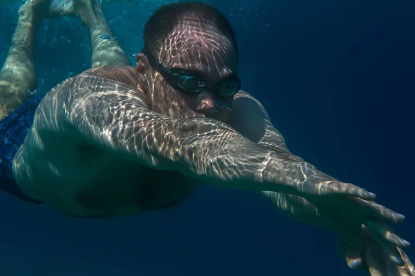 Hombre de turismo nadando gafas deportivas nadando bajo el agua en el mar Egeo en la costa de la península de Sithonia —  Fotos de Stock