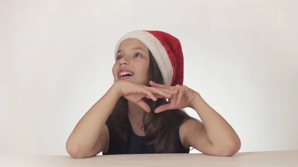 Menina feliz bonita adolescente em um olhar de chapéu de Papai Noel e emocionalmente expressa uma surpresa no fundo branco — Fotografia de Stock