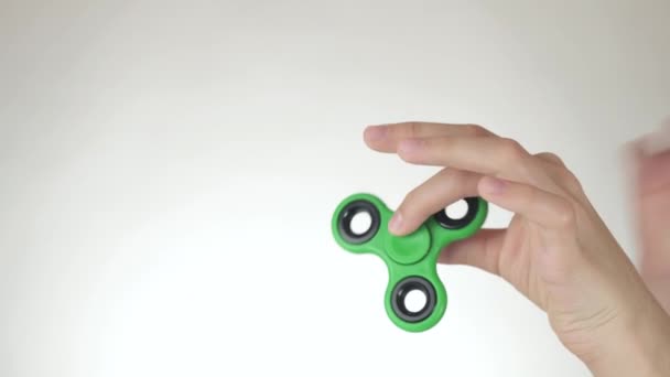 Händerna på en tonårig flicka snurra en grön fidget spinner på vit bakgrund arkivfilmer video — Stockvideo