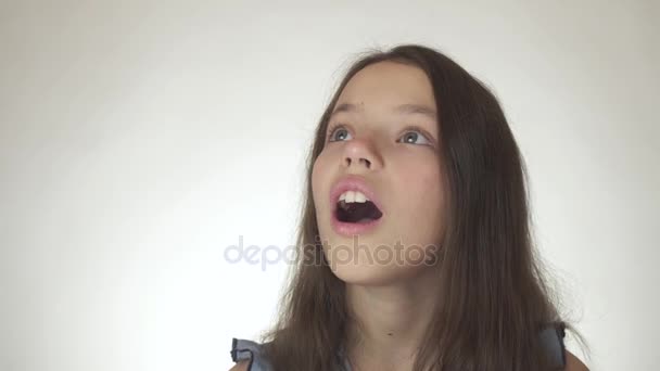 Menina adolescente feliz bonita olha para cima e é surpreendido close-up no fundo branco imagens de vídeo — Vídeo de Stock