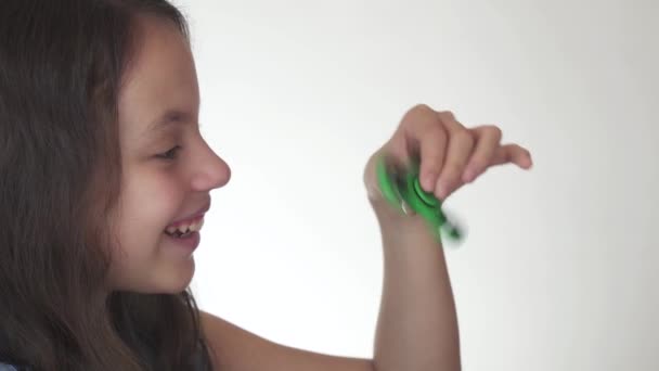 Hermosa alegre adolescente chica jugando con verde fidget spinner en blanco fondo material material material vídeo — Vídeo de stock