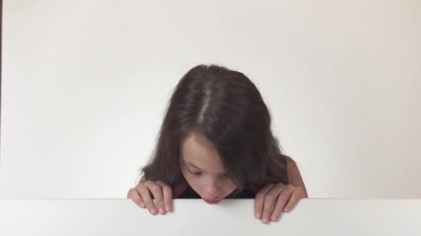 Bella ragazza adolescente guarda un poster con informazioni e felicemente sorpreso su sfondo bianco stock filmato video . — Video Stock