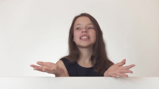 Menina bonita adolescente mantém um pôster com informações e alegremente anuncia-lo em fundo branco imagens de vídeo . — Vídeo de Stock
