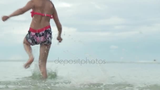 Alegre feliz joven corriendo en agua mar spray cámara lenta archivo de vídeo — Vídeos de Stock