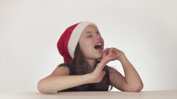 Linda menina feliz adolescente em um chapéu de Papai Noel emocionalmente canta no fundo branco imagens de vídeo . — Vídeo de Stock