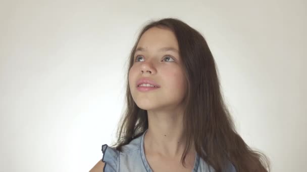 Hermosa chica adolescente feliz mira hacia arriba y sonriendo de cerca en el fondo blanco material de archivo de vídeo — Vídeo de stock