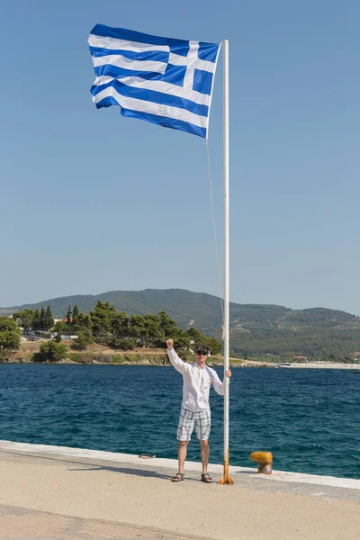 Turista vicino alla bandiera greca sulla costa egea della penisola di Sithonia — Foto Stock